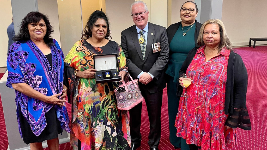 Denise with govt official and family members, holding OAM award