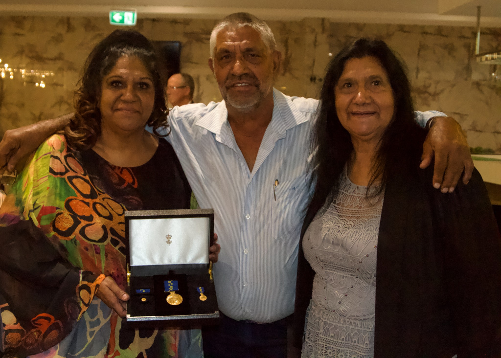 Denise Smith-Ali, with sister Beverley Rebbeck and brother Noel Smith, holding Denise's OAM Award